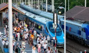 Tłum ludzi na peronie czeka na pociąg Pendolino. Widoczne są różne trasy kolejowe i nowoczesne składy.