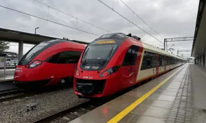 Dwa czerwone pociągi SKM stojące na peronie.
