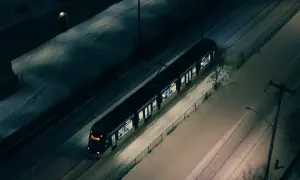 Pociąg Warszawskiej Kolei Dojazdowej mija ośnieżone tereny nocą.