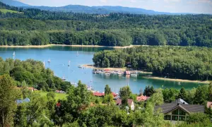 Malowniczy widok na Jezioro Solińskie z żaglówkami i lasami. Idealne miejsce, by sprawdzić, jak dojechać nad Solinę samochodem i odpocząć.