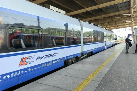 Pociąg PKP Intercity na peronie, z widocznymi oknami i logo przewoźnika.