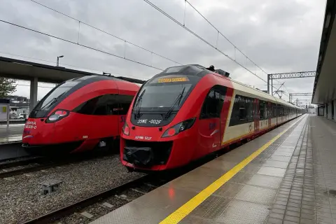 Dwa czerwone pociągi SKM stojące na peronie.