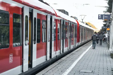 Czerwono-biały pociąg PKP z otwartymi drzwiami na peronie, ludzie czekają.