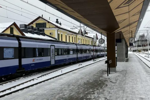 Pociąg PKP Intercity na stacji w Żaganiu, zimowy dzień. Zielona góra w oddali, śnieg na torach i peronie.