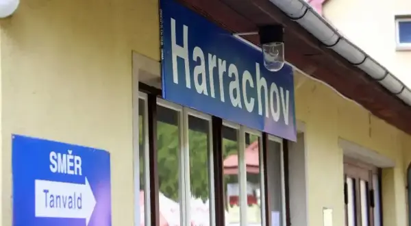 Tabliczka "Harrachov" nad oknami dworca. Obok znak "Směr Tanvald", wskazujący kierunek podróży pociągiem z Szklarskiej Poręby do Harrachova.