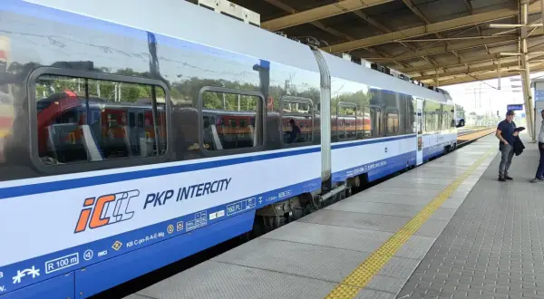 Pociąg PKP Intercity na peronie, z widocznymi oknami i logo przewoźnika.