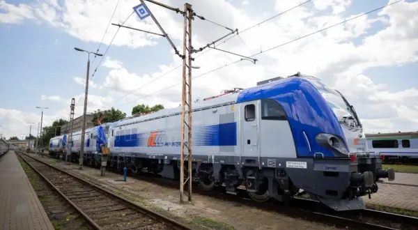 Nowe lokomotywy PKP Intercity, gotowe do podróży z Lublina. Zielona góra w tle, chmury na niebie.