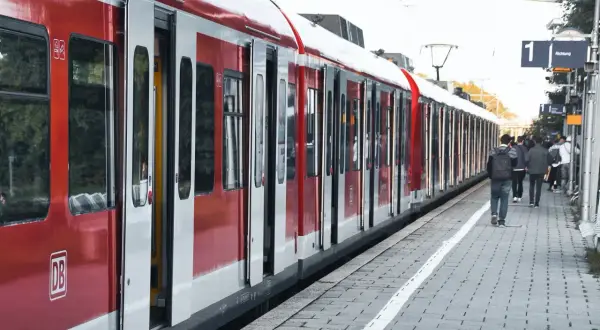 Czerwono-biały pociąg PKP z otwartymi drzwiami na peronie, ludzie czekają.