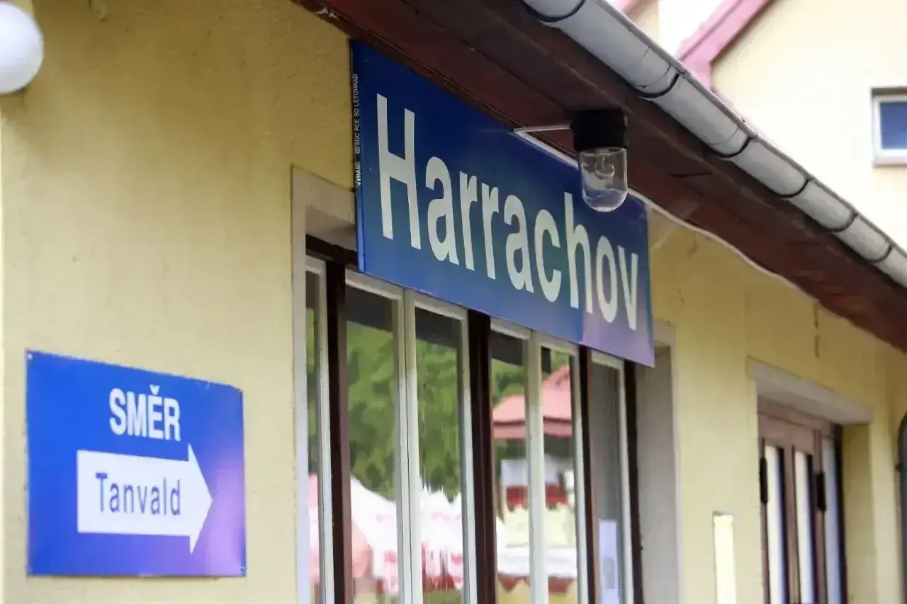 Tabliczka "Harrachov" nad oknami dworca. Obok znak "Směr Tanvald", wskazujący kierunek podróży pociągiem z Szklarskiej Poręby do Harrachova.