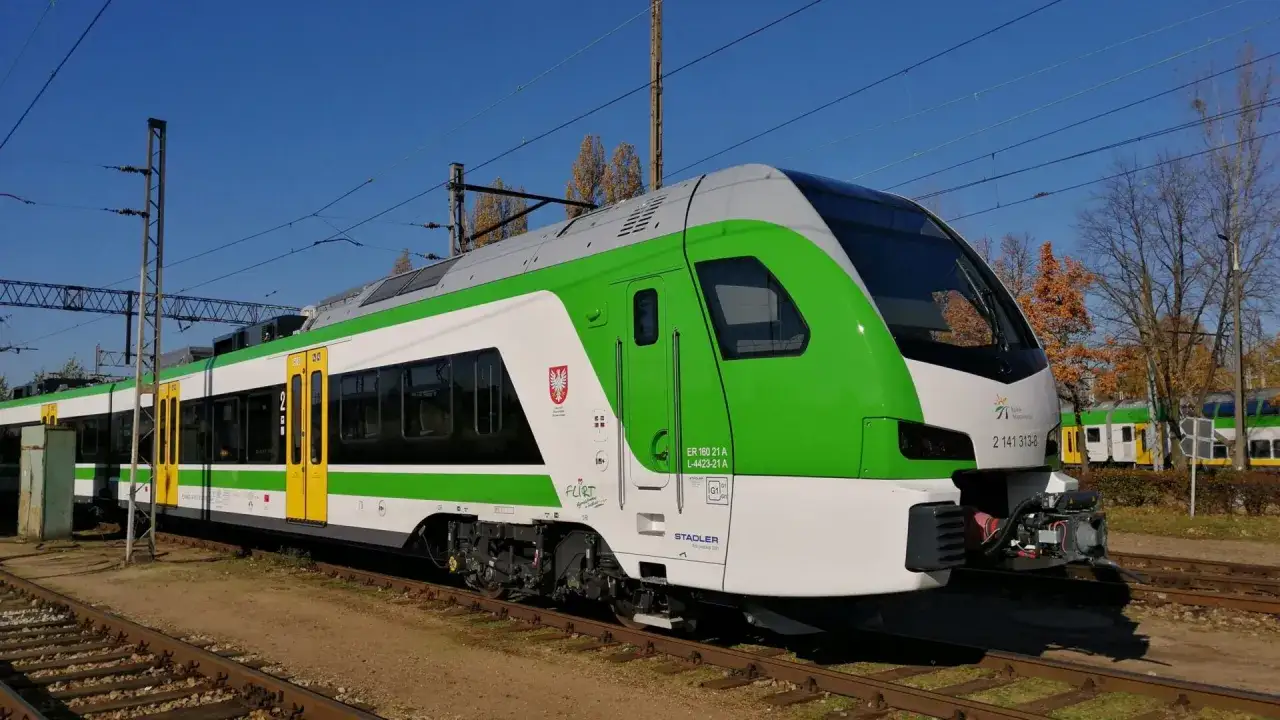 Nowoczesny pociąg słoneczny w zielono-białych barwach stoi na torach.