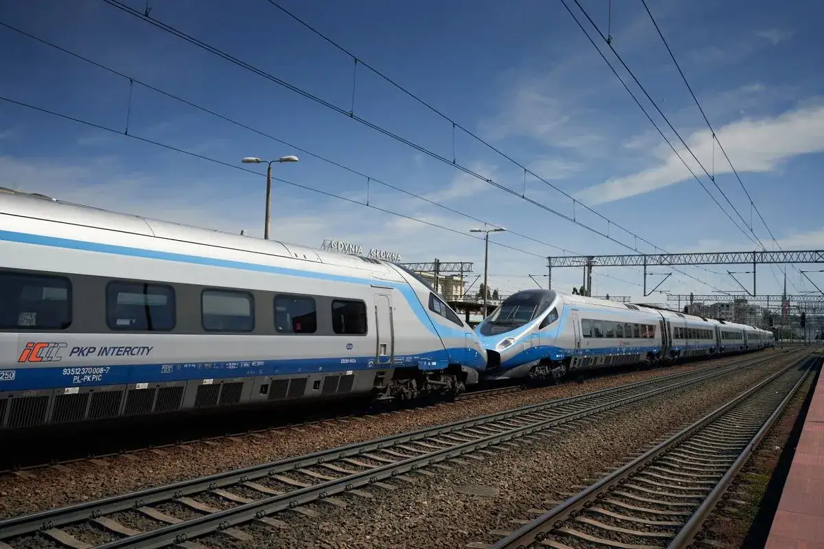 Dwa nowoczesne pociągi PKP Intercity, jeden z nich to pociąg Rzeszów-Gdańsk, stoją obok siebie na torach przy peronie.