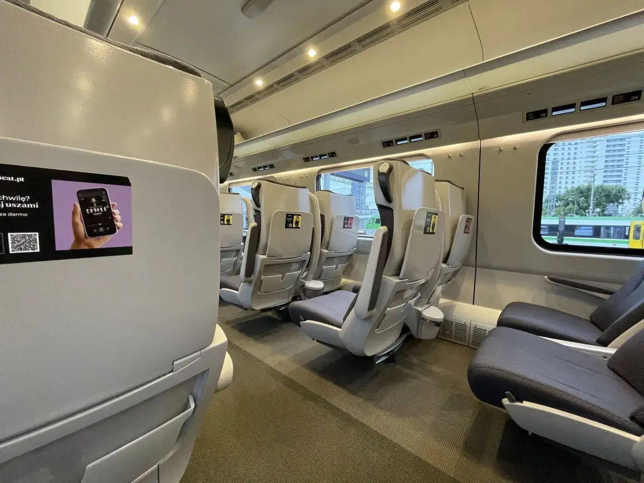 Wnętrze pociągu Pendolino, klasa 1 i 2. Puste, wygodne fotele w jasnej kolorystyce, gotowe na podróżnych.