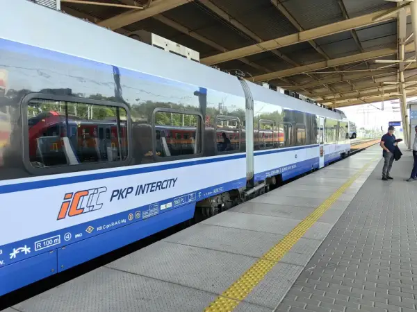 Pociąg PKP Intercity na peronie, z widocznymi oknami i logo przewoźnika.